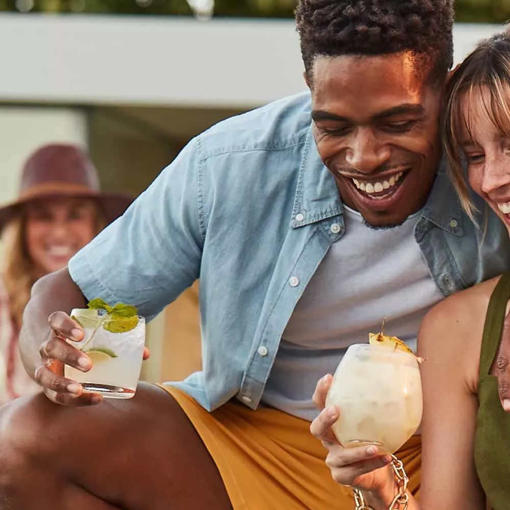 Young couple enjoying Cruzan cocktails as they sit outside.