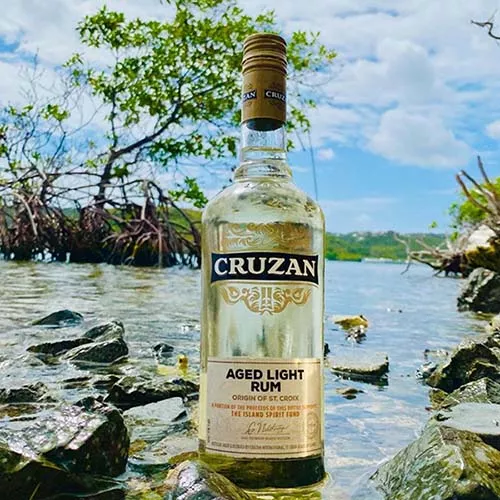 Image of Cruzan Aged Light Rum set atop the water in St. Croix.  